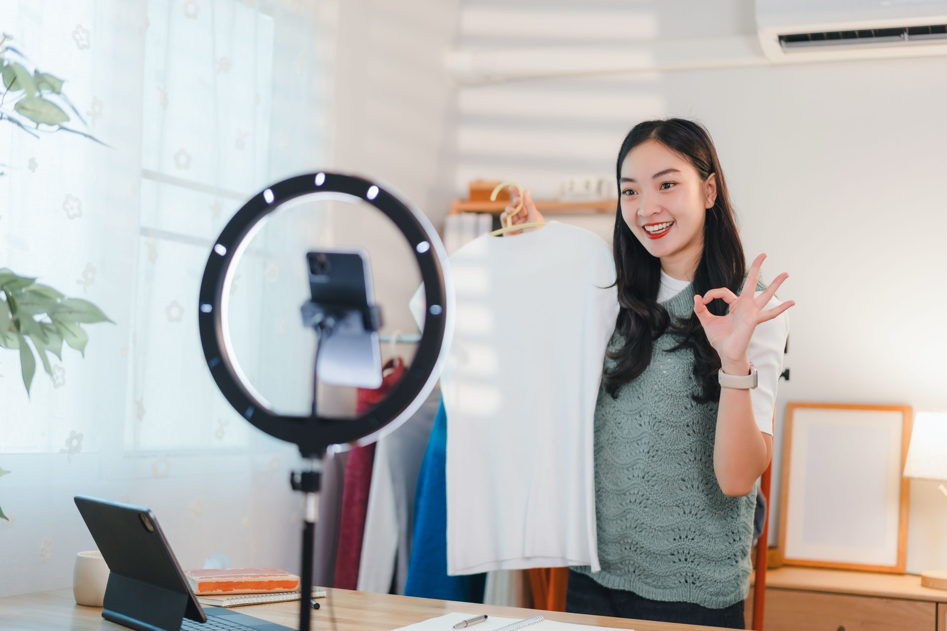 woman livestreaming product reviews with ring light and smartphone in cozy home setting